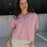 Front view of model wearing the Elise Pink Cropped Short Sleeve Tee that has pink knit fabric, a button up neckline, a chest pocket, and short sleeves.