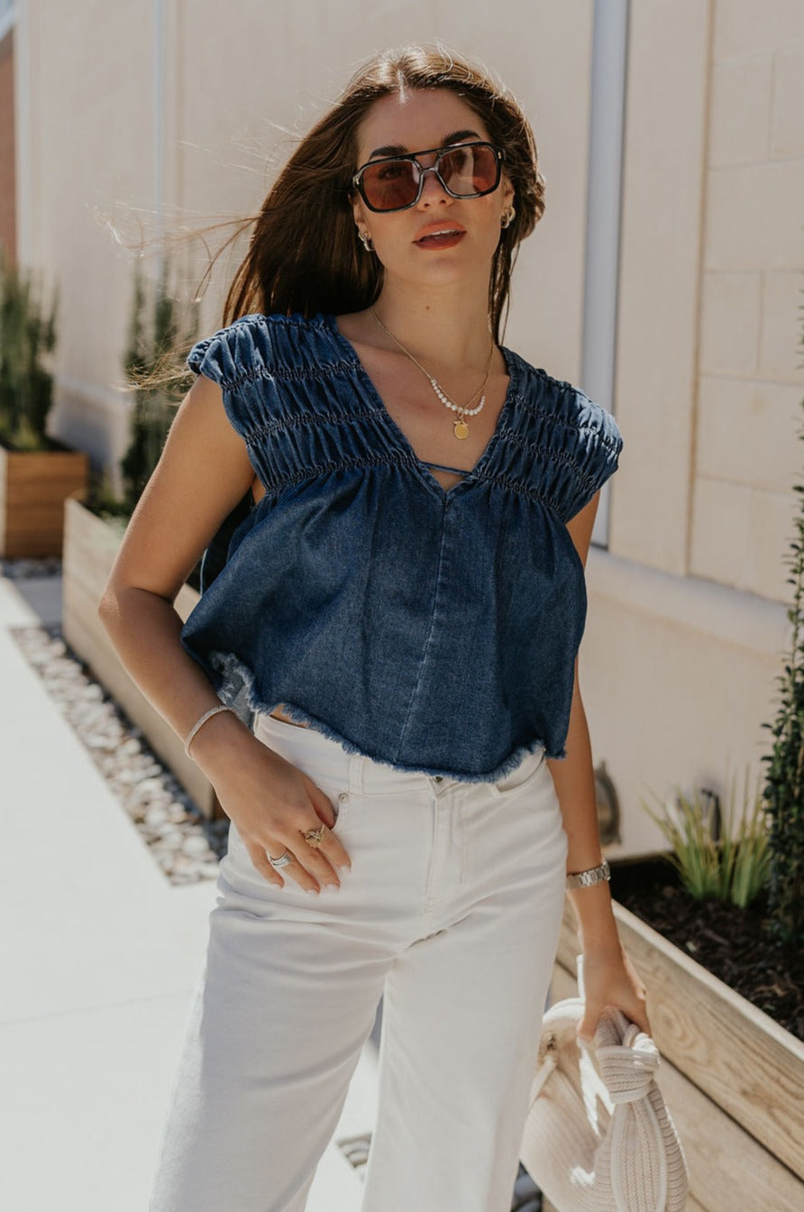 Front view of female model wearing the Chloe Medium Denim Fray Sleeveless Top which features Medium Denim Blue Fabric, Fray Hem, Upper Ruched Details, V-Neckline and Sleeveless