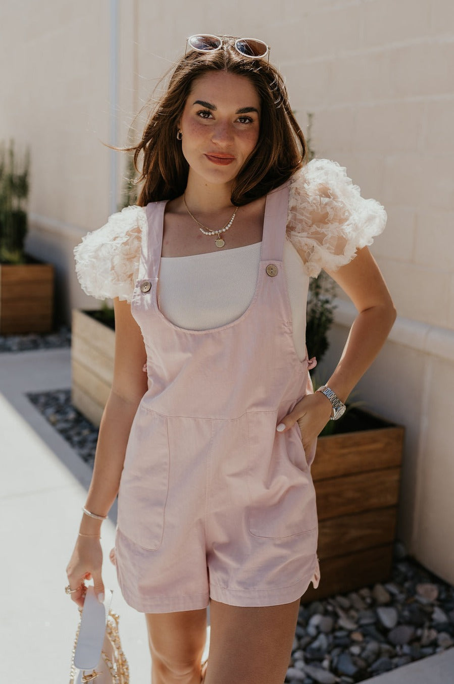Front view of female model wearing the Selah Mauve Pink Sleeveless Romper which features Mauve Pink Lightweight Fabric, Pockets On Each Side, Slight Slit Details, Scoop Neckline, Straps with Wooden Button Closures and Sleeveless