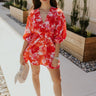 Full body front view of female model wearing the Brittany Red & Pink Floral Mini Dress that has red and pink floral print, a plunge neck, elastic waist, and puff sleeves.