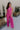 Full body front view of female model wearing the Baylee Magenta Convertible Jumpsuit that has magento fabric, wide legs, and a neckline that can be halter or a front tie strapless neck. Shown as halter.