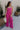 Full body front view of female model wearing the Baylee Magenta Convertible Jumpsuit that has magento fabric, wide legs, and a neckline that can be halter or a front tie. Shown as strapless.