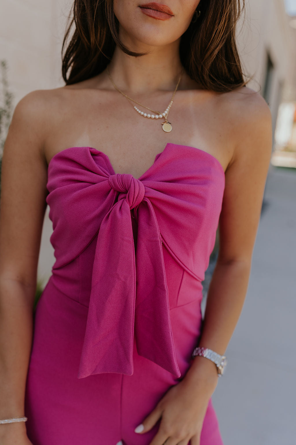 Close front view of female model wearing the Baylee Magenta Convertible Jumpsuit that has magento fabric, wide legs, and a neckline that can be halter or a front tie. Shown as strapless.