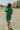 Full body back view of female model wearing the Paulina Green Quilted Shorts that have green quilted fabric, a drawstring elastic waist, and side pockets. Worn with matching top
