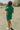 Full body back view of female model wearing the Paulina Green Quilted Quarter Zip-Up Top which features Kelly Green Knit Cotton Fabric, Monochrome Quilt Pattern Detail, Ribbed Hem, Slight Crop Waist, Quarter Zip-Up and Sleeveless