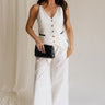 Full body view of female model wearing the Amelia Off White & Black Wide Leg Pants which features  Off White Linen Fabric, Black Trim Details, Front Pockets, Wide Pant Legs, Front Zipper with Tortoise Button Closure and Belt Loops