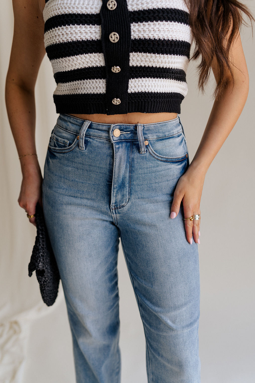 close up view of female model wearing the Eliana Medium Wash Straight Leg Jeans which features Medium Wash Denim Fabric, Straight Leg, High Waist, Two Front Pockets, Two Back Pockets, Front Zipper with Button Closure and Belt Loops