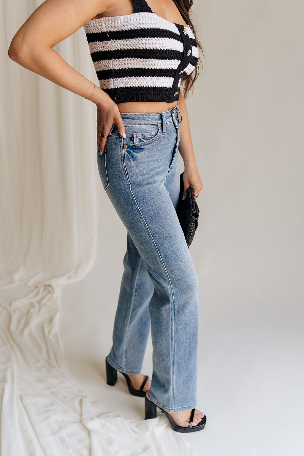 side view of female model wearing the Eliana Medium Wash Straight Leg Jeans which features Medium Wash Denim Fabric, Straight Leg, High Waist, Two Front Pockets, Two Back Pockets, Front Zipper with Button Closure and Belt Loops