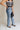 side view of female model wearing the Eliana Medium Wash Straight Leg Jeans which features Medium Wash Denim Fabric, Straight Leg, High Waist, Two Front Pockets, Two Back Pockets, Front Zipper with Button Closure and Belt Loops