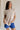 Front view of female model wearing the Arana Knit Short Sleeve Top which features Lightweight Knit Fabric, Slight Slit Details, Front Left Chest Pocket, Round Neckline and Short Sleeves. the top is available in beige and mauve