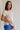 side view of female model wearing the Arana Knit Short Sleeve Top which features Lightweight Knit Fabric, Slight Slit Details, Front Left Chest Pocket, Round Neckline and Short Sleeves. the top is available in beige and mauve