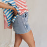 Close side view of female model wearing the Hailey Silver Stud Denim Shorts that have light wash denim, silver stud details, pockets, and a front zipper.