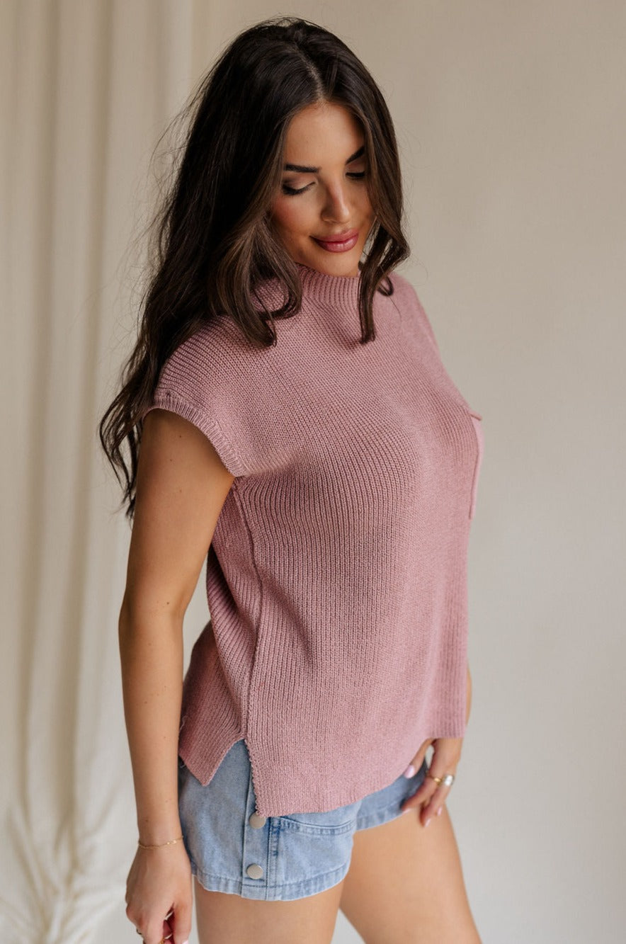 side view of female model wearing the Arana Knit Short Sleeve Top which features Lightweight Knit Fabric, Slight Slit Details, Front Left Chest Pocket, Round Neckline and Short Sleeves. the top is available in beige and mauve