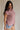 side view of female model wearing the Arana Knit Short Sleeve Top which features Lightweight Knit Fabric, Slight Slit Details, Front Left Chest Pocket, Round Neckline and Short Sleeves. the top is available in beige and mauve