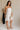 full body side view of female model wearing the Lucia White Eyelet Strapless Mini Dress which features White Eyelet Pattern, White Lining, Mini Length, Flare Hem Skirt and Strapless