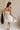 back view of female model wearing the Lucia White Eyelet Strapless Mini Dress which features White Eyelet Pattern, White Lining, Mini Length, Flare Hem Skirt and Strapless