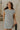 Upper body front view of model wearing the Gabriella Cream & Black Striped Mini Dress that has cream fabric with horizontal black stripes, a sleeveless body, round neck, and side pockets.