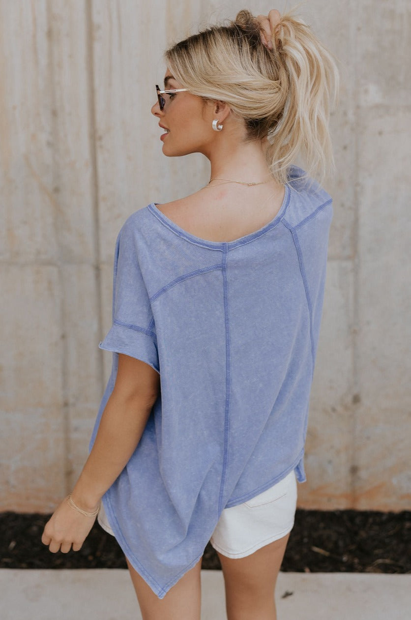 Back view of female model wearing the Nova Thread Short Sleeve Top which features Cotton Fabric, Curved Hem Details, Round Neckline and Shorts Sleeves. the top is available in blue and white