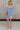 Full body back view of female model wearing the Nova Thread Short Sleeve Top which features Cotton Fabric, Curved Hem Details, Round Neckline and Shorts Sleeves. the top is available in blue and white