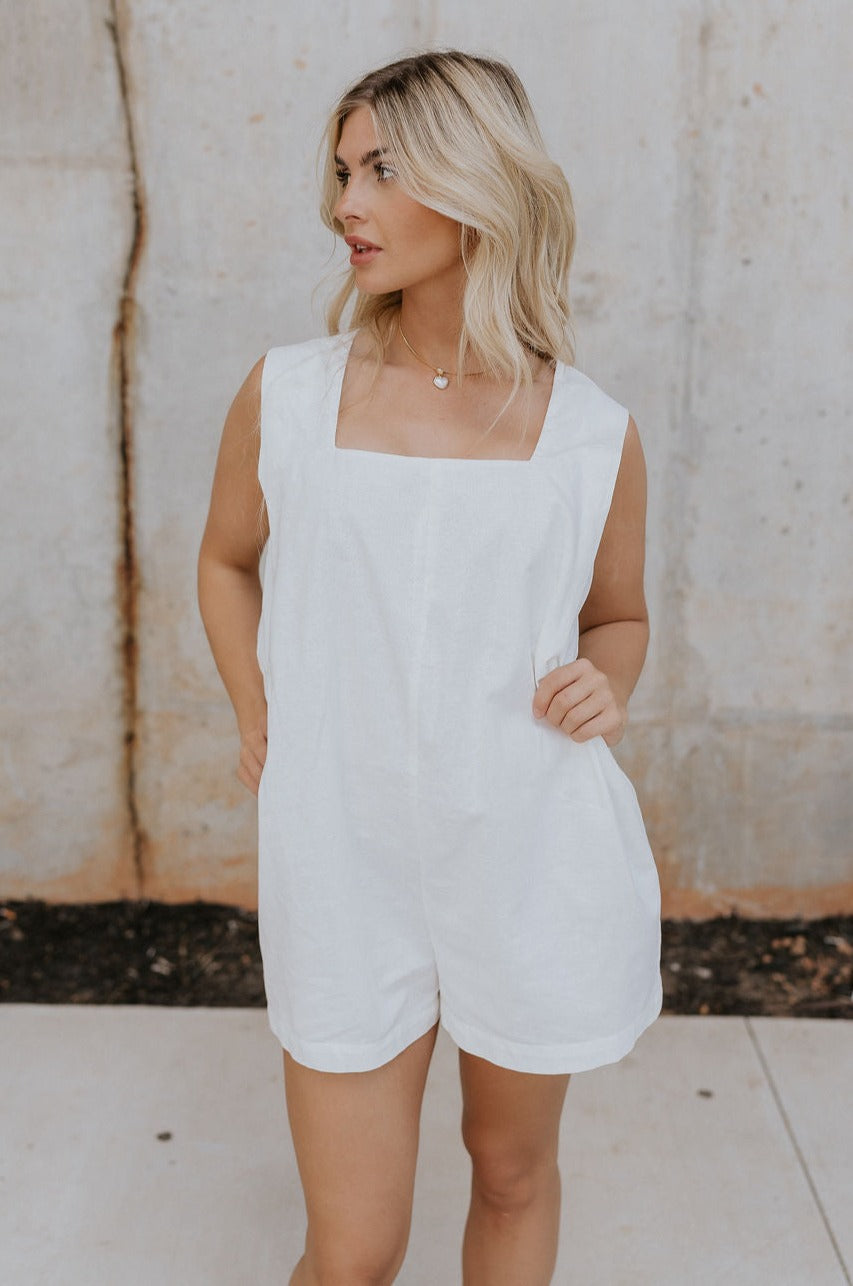 Front view of female model wearing the Teagan White Square Neckline Romper which features White Linen Fabric, White Lining. Square Neckline, Sleeveless and Monochrome Back Zipper with Hook Closure