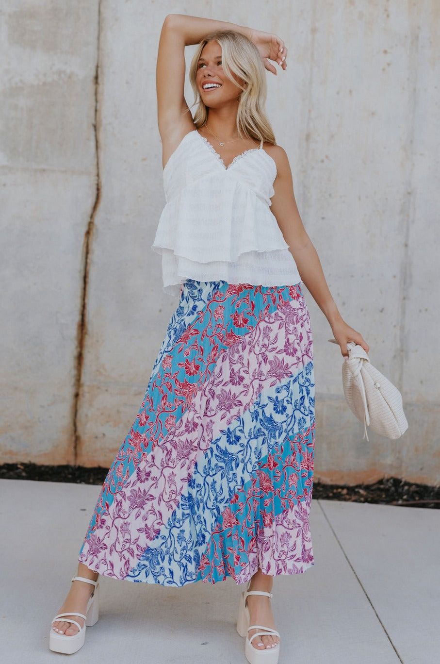 Full body view of female model wearing the Lily Aqua & Pink Multi Pleated Maxi Skirt which features Blue, Pink, Red, Purple and Aqua Floral Print, Satin Pleated Fabric, Maxi Length, Light Blue Lining and Side Zipper with Hook Closure