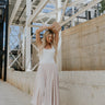 Front view of female model wearing the April Taupe Midi Skirt.  This features an elastic waist band and a flowy shape.