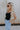 side view of female model wearing the Leigh Square Neckline Sleeveless Tank which features Ribbed Lightweight Fabric, Square Neckline and Sleeveless. the tank is available in white and black.