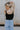back view of female model wearing the Leigh Square Neckline Sleeveless Tank which features Ribbed Lightweight Fabric, Square Neckline and Sleeveless. the tank is available in white and black.