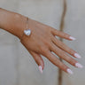 The hand of a model is shown with the Gia Heart Bracelet clasped on her wrist.