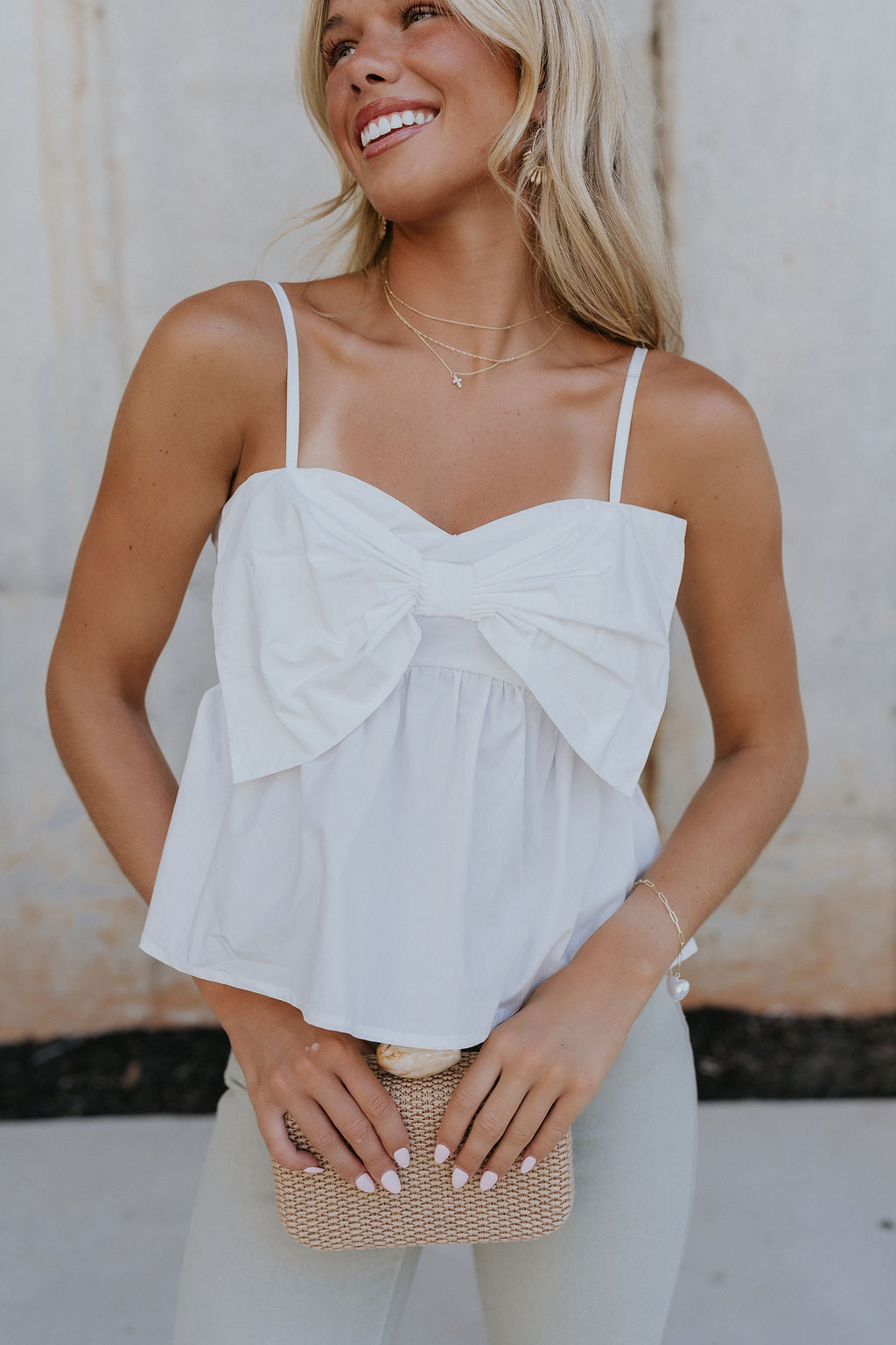 Close up view of female model wearing the Alina Off White Bow Poplin Tank which features White Lightweight Fabric, Cropped Waist, Front Oversized Bow Detail, Adjustable Straps and Monochrome Back Zipper with Hook Closure