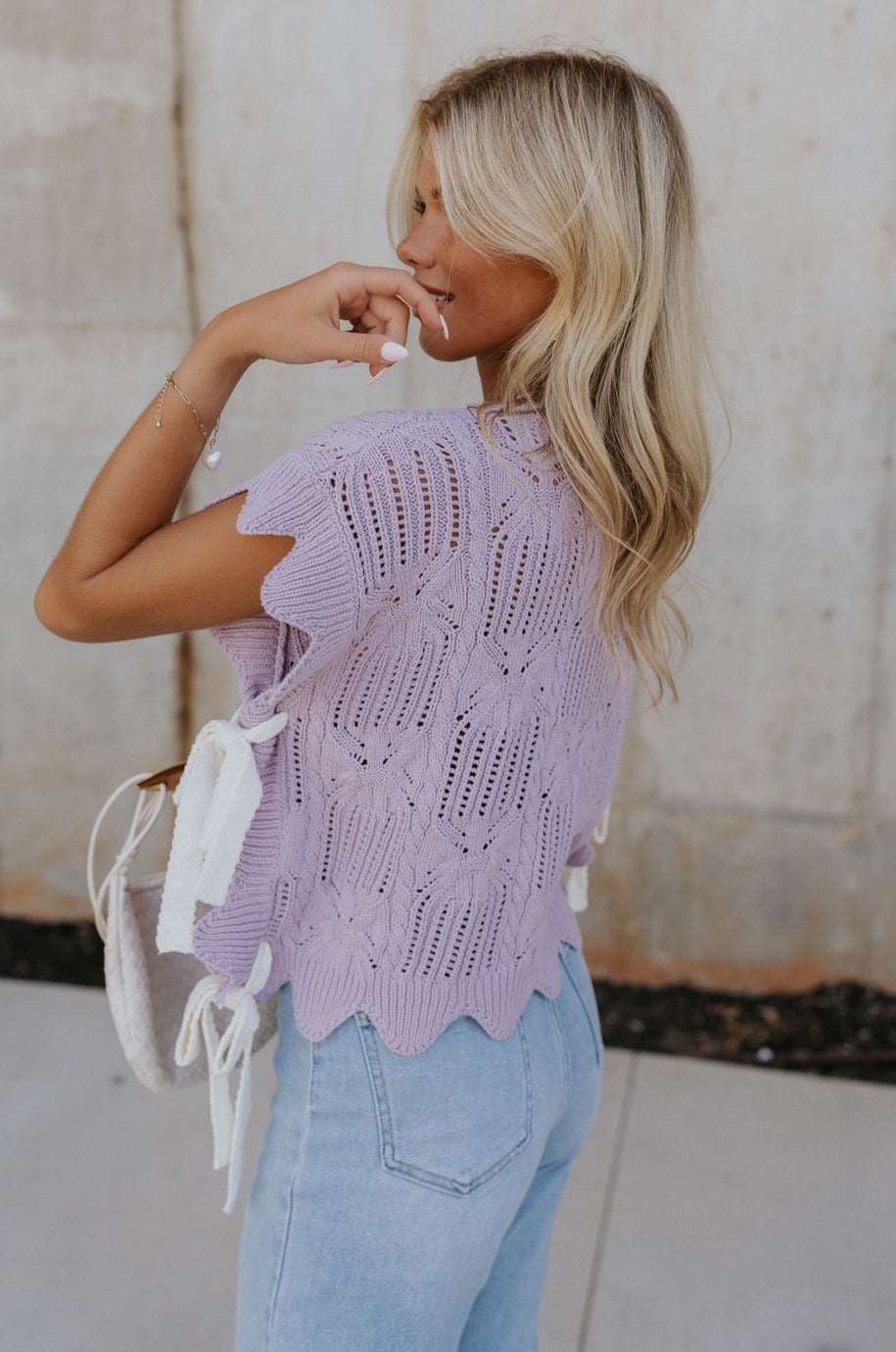 Side view of female model wearing the Full body view of female model wearing the Camille Lavender Knit Side Ties Short Sleeve Top which features Lavender Knit Fabric, Short Sleeves, Round Neckline, Scalloped Hem Details and Cream Side Tie Details