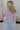 back view of female model wearing the Full body view of female model wearing the Camille Lavender Knit Side Ties Short Sleeve Top which features Lavender Knit Fabric, Short Sleeves, Round Neckline, Scalloped Hem Details and Cream Side Tie Details