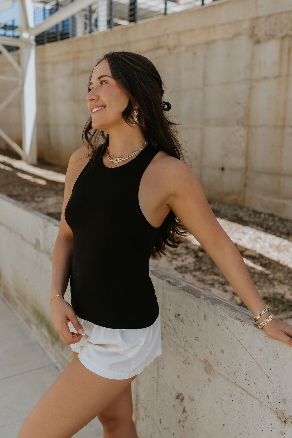side view of female model wearing the Lianna Black Sleeveless Tank which features Black Lightweight Fabric, Black Lining, Round Neckline and Sleeveless