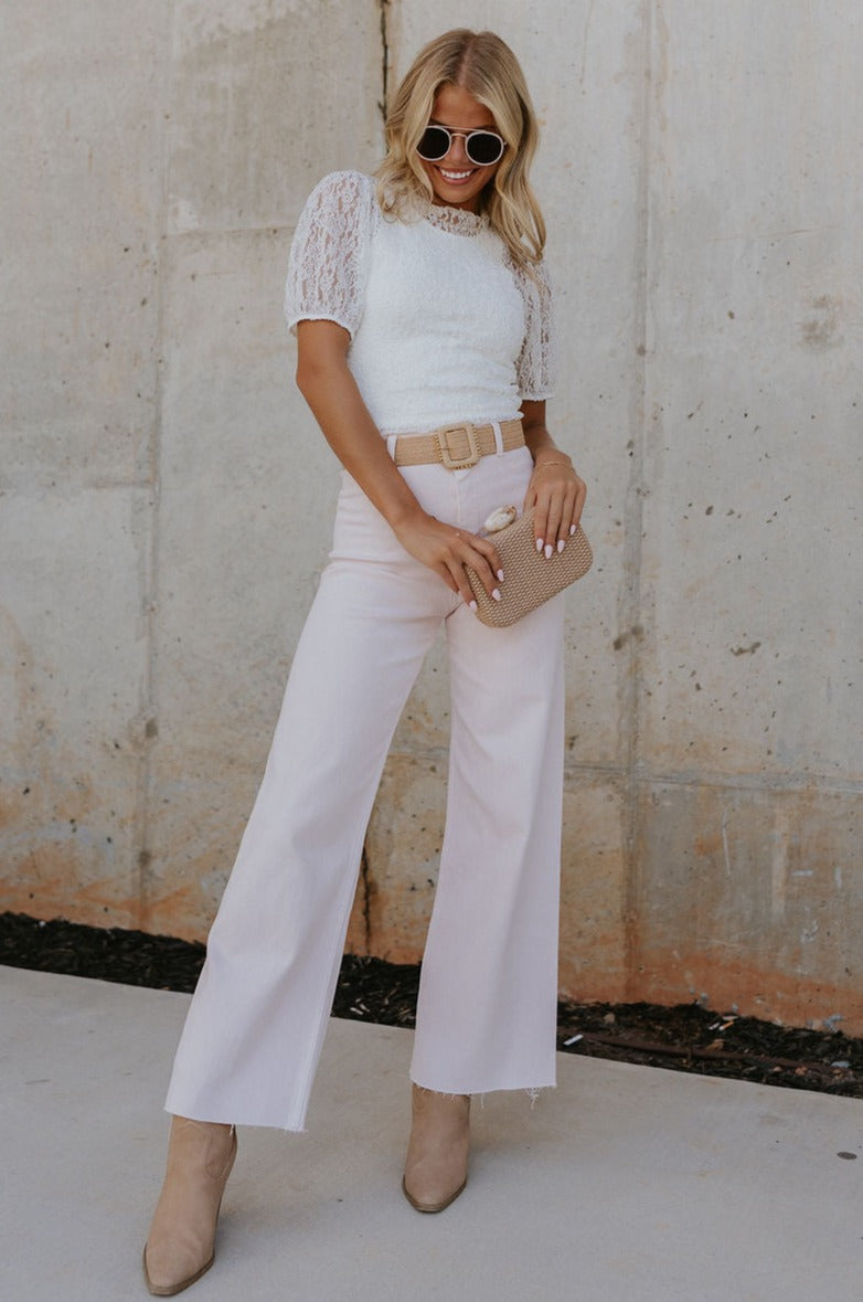 Full body view of female model wearing the Charli Cropped Wide Leg Pants which features Denim-Like Fabric, Wide Pant Legs, Raw Hem, Monochrome Front Button with Zipper Closure, Two Front Pockets, Two Back Pockets and Belt Loops. the pants are available in blue and pink.