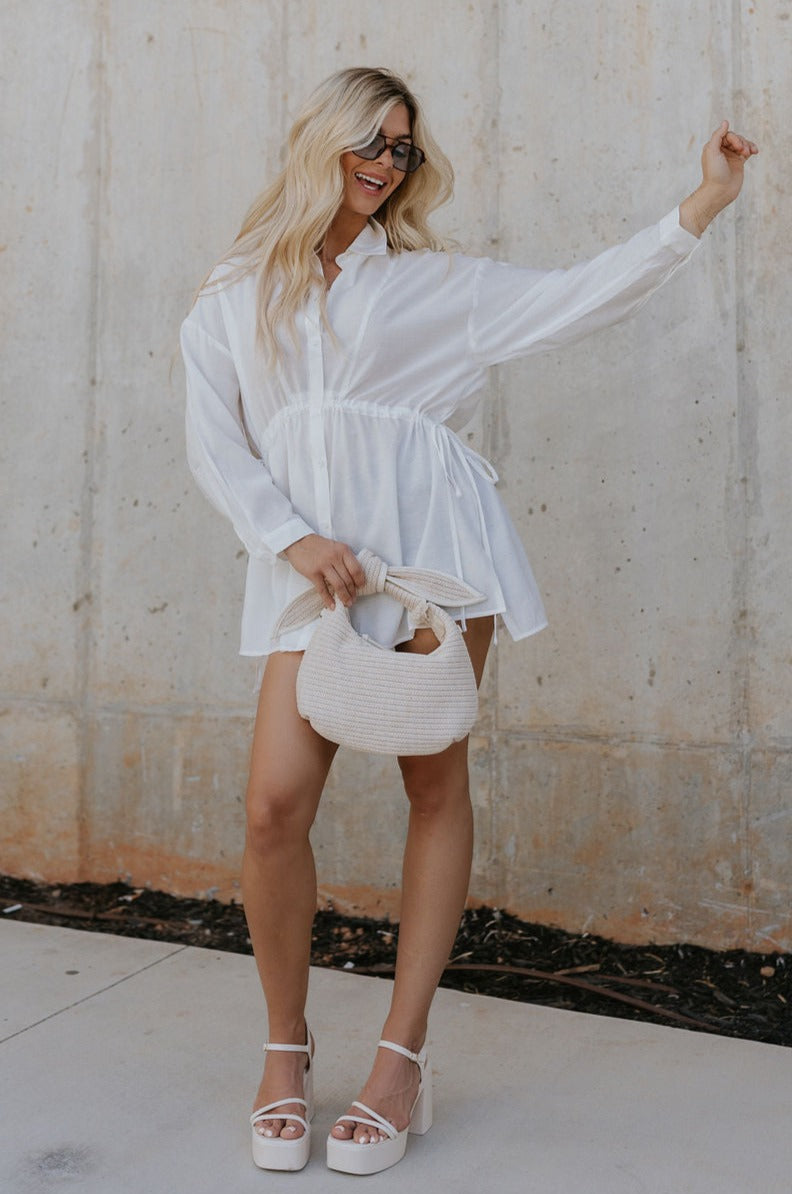 Full body view of female model wearing the Laura Off White Drawstring Cinched Long Sleeve Top which features Off White Lightweight Fabric, Slit Hem Details, Front Button-Up, Adjustable Cinch Waistband,  Collared Neckline and Long Sleeves with Buttoned Cuffs