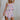 front view of female model wearing the Skye Pink Multi Floral Shorts which features Purple, Pink and Peach Floral Print, White Shorts Lining, Front Skirt Overlay with Wooden Button Closure and Back Zipper with Hook Closure
