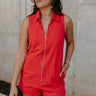 Front view of female model wearing the Athena Front Zip-Up Halter Romper which features Denim Like Fabric, Pockets on each side, Two Back Pockets, Folded Hem Details, Front Zipper Closure, Collared Neckline and Sleeveless. the romper is available in red and black