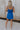 Full body back view of female model wearing the Grace Side Ruched Square Neckline Mini Dress which features Lightweight Linen Fabric, Fully Lined, Mini Length, Square Neckline, Ruched Side Detail, Adjustable Straps and Monochrome Back Zipper with Hook Closure. the dress is available in blue and white