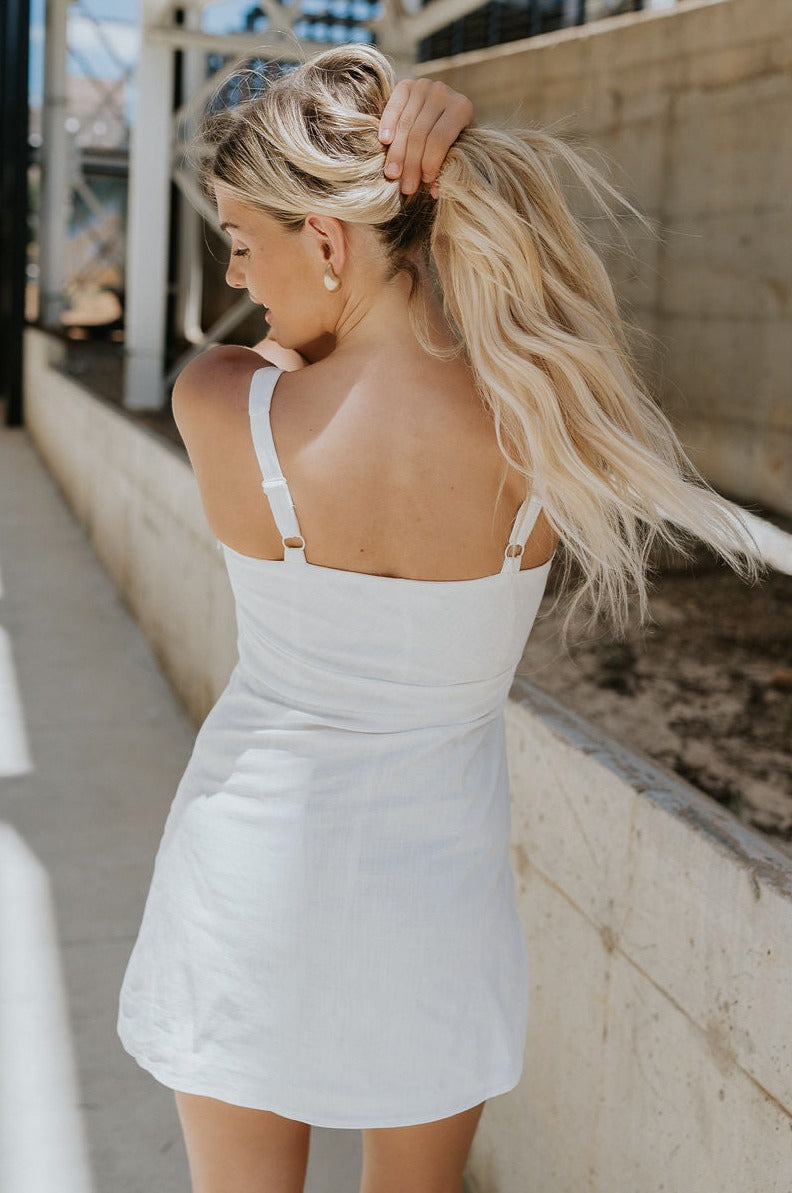 Back view of female model wearing the Grace Side Ruched Square Neckline Mini Dress which features Lightweight Linen Fabric, Fully Lined, Mini Length, Square Neckline, Ruched Side Detail, Adjustable Straps and Monochrome Back Zipper with Hook Closure. the dress is available in blue and white