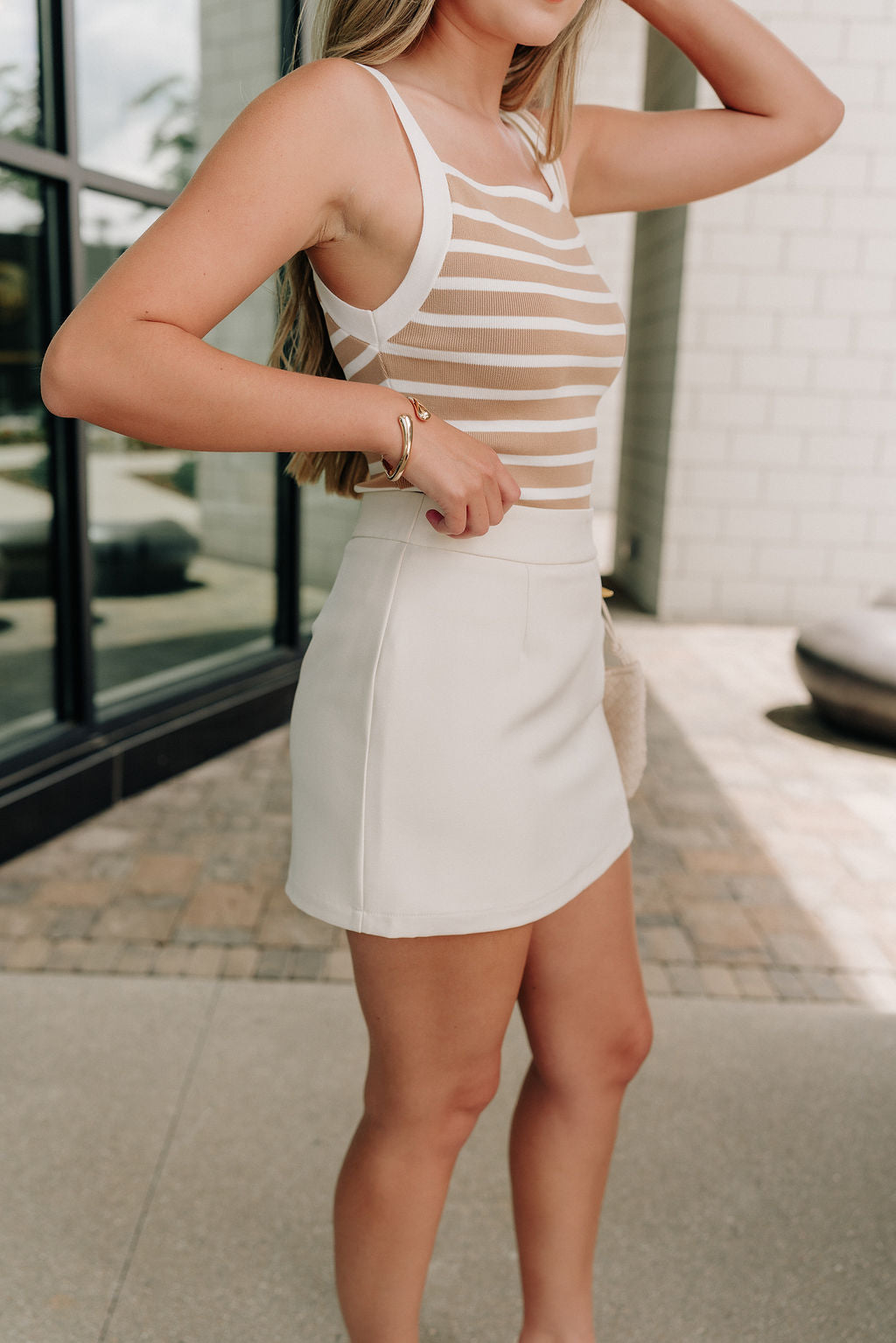 side view of female model wearing the Isabella Cream Mini Skort which features Cream Lightweight Fabric, Mini Length, Cream Shorts Lining and Monochrome Size Zipper with Hook Closure
