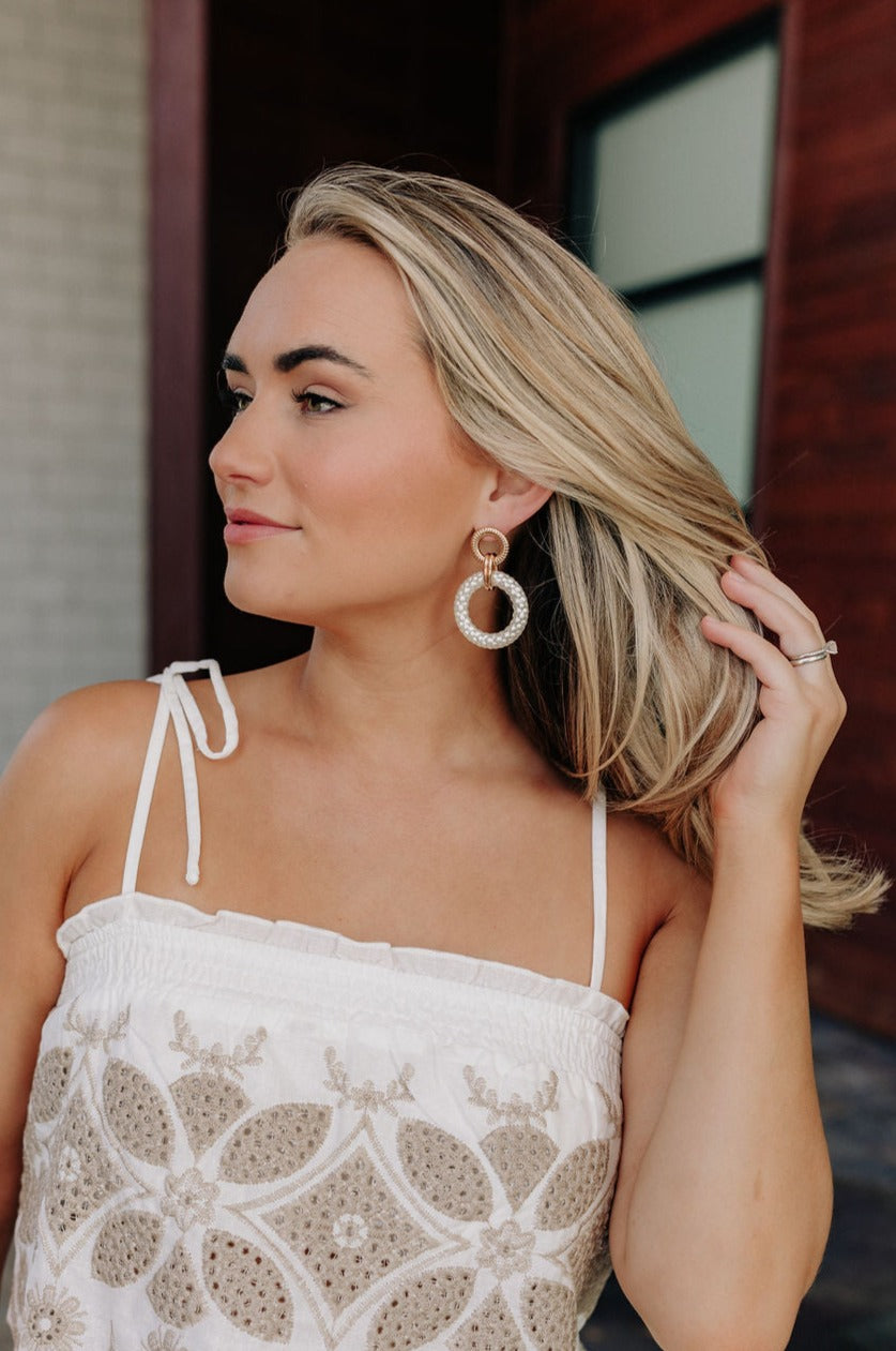 Side view of female model wearing the Skyler White & Gold Dangle Earrings that have gold circles attached to white dangle circles.