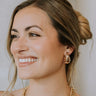 Side view of female model wearing the Katie Gold & Pearl Scoop Studs that have gold scoop studs with small pearl polka dots
