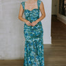 Full body view of female model wearing the Khloe Blue & Green Floral Ruched Midi Dress which features Blue and Green Floral Print, Ruched Fabric, Flare Skirt Hem with Slit, Sweetheart Neckline, Straps and Monochrome Side Zipper with Hook Closure