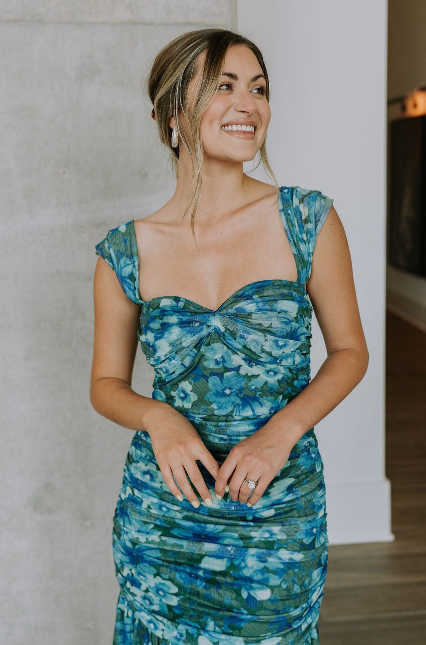 front view of female model wearing the Khloe Blue & Green Floral Ruched Midi Dress which features Blue and Green Floral Print, Ruched Fabric, Flare Skirt Hem with Slit, Sweetheart Neckline, Straps and Monochrome Side Zipper with Hook Closure