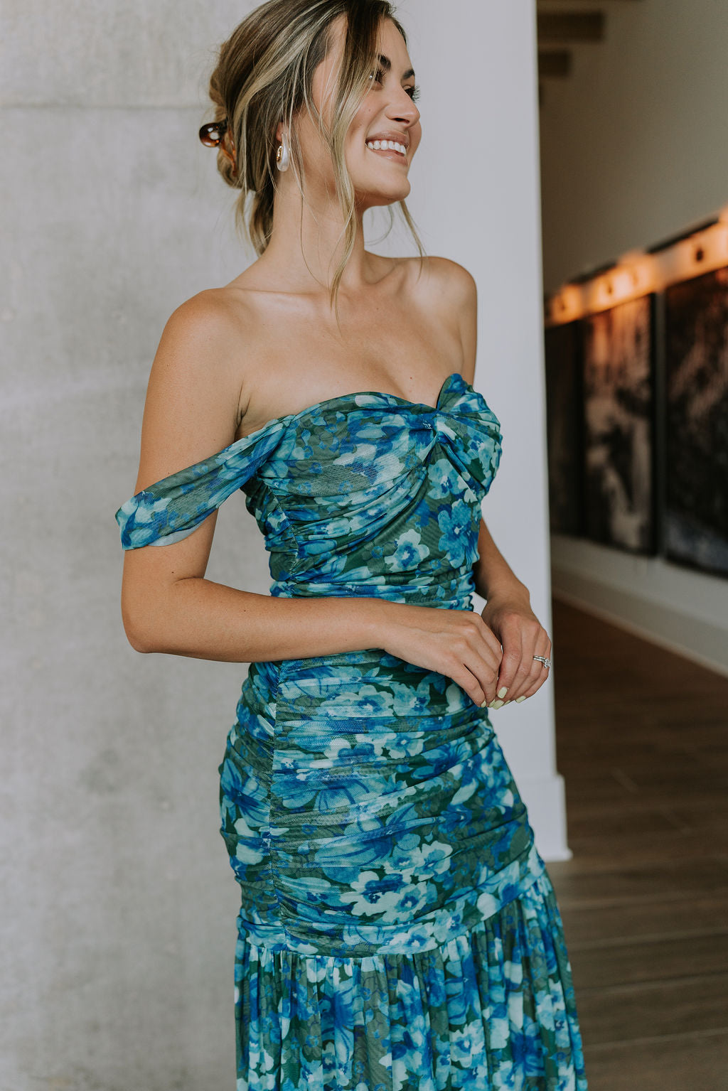 side view of female model wearing the Khloe Blue & Green Floral Ruched Midi Dress which features Blue and Green Floral Print, Ruched Fabric, Flare Skirt Hem with Slit, Sweetheart Neckline, Straps and Monochrome Side Zipper with Hook Closure