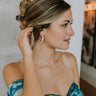 Side view of female model wearing Faye White & Gold Teardrop Hoops that have pearlescent white teardrop-shaped hoops with gold trim