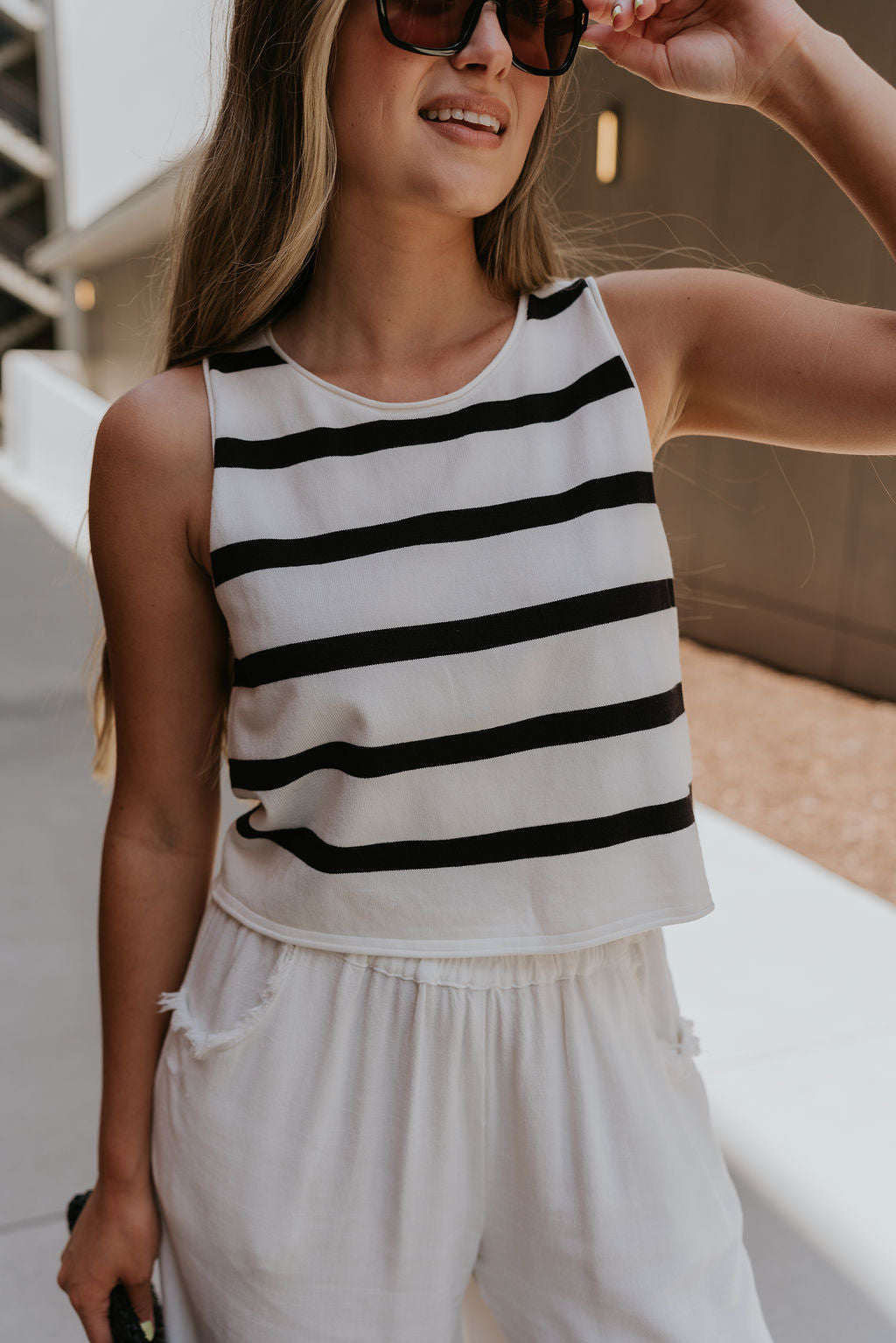 close up view of female model wearing the Mallory Off White & Black Stripe Tank which features White and Black Stripe Pattern, Round Neckline, Cropped Waist and Sleeveless