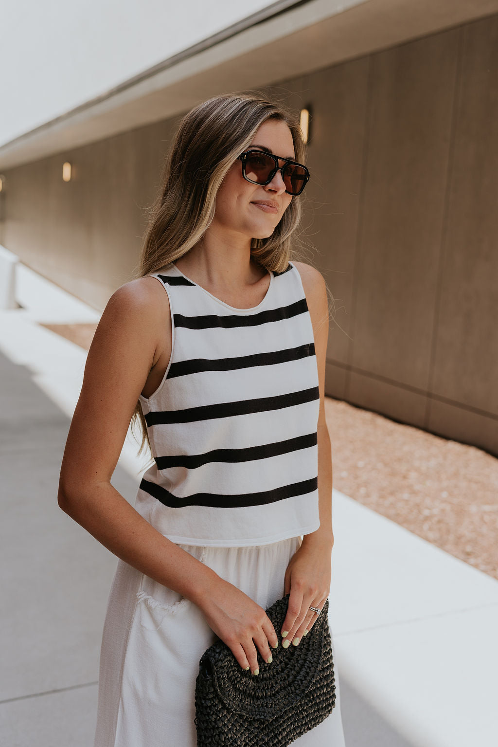 frontal side view of female model wearing the Mallory Off White & Black Stripe Tank which features White and Black Stripe Pattern, Round Neckline, Cropped Waist and Sleeveless