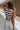 back view of female model wearing the Mallory Off White & Black Stripe Tank which features White and Black Stripe Pattern, Round Neckline, Cropped Waist and Sleeveless