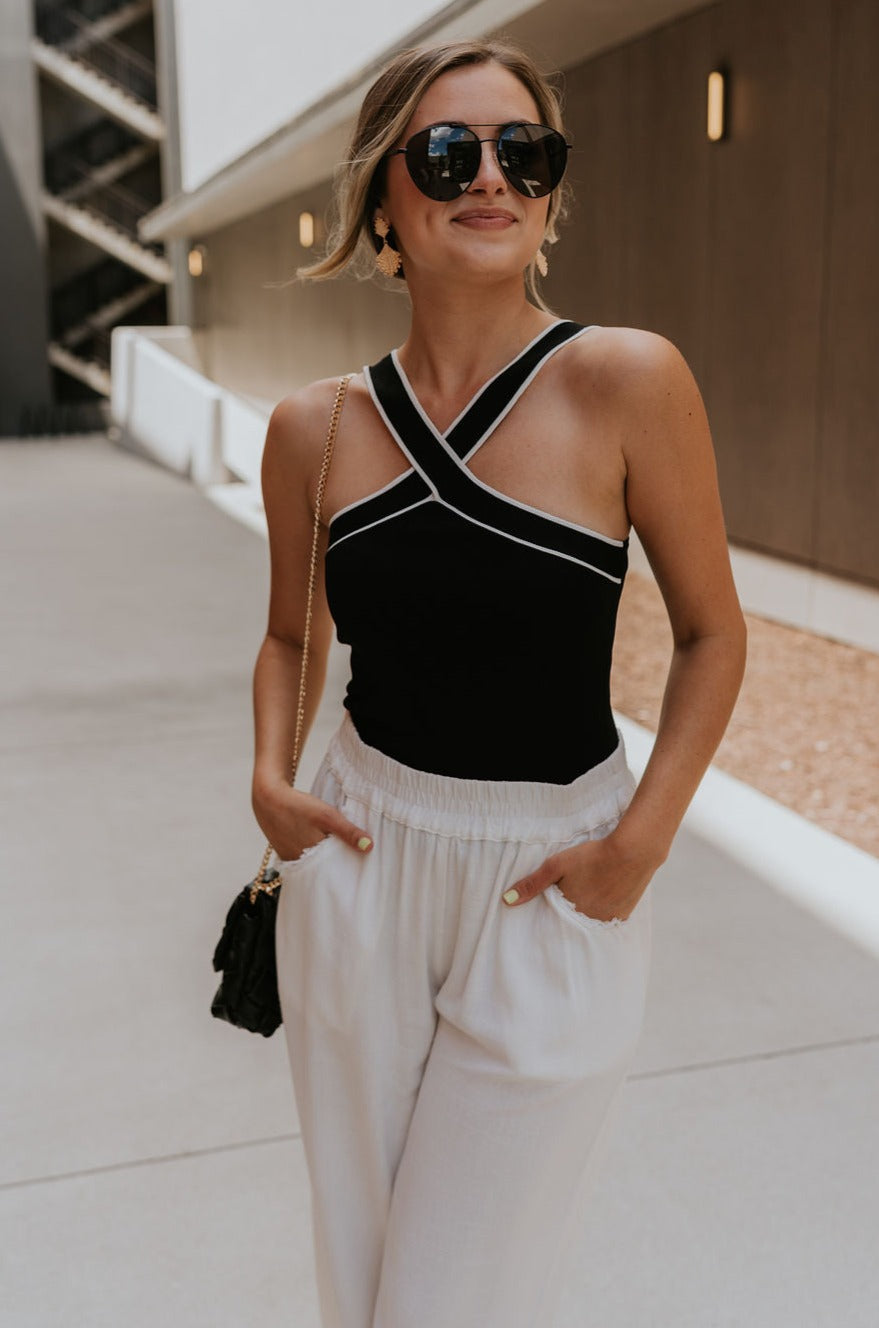 front view of female model wearing the Jane Criss-Cross Halter Tank which features Lightweight Ribbed Fabric, Cropped Tank and Halter Neckline. the tank is available in black and white